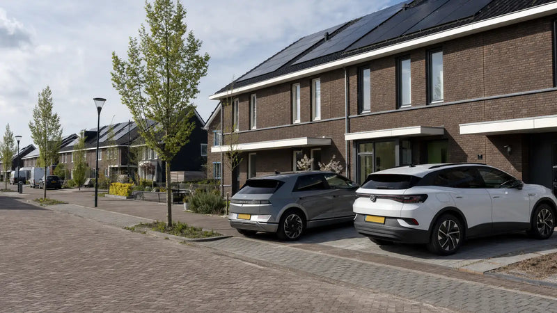 Nieuwbouwwijk met zonnepanelen op de daken en elektrische auto's op de opritten